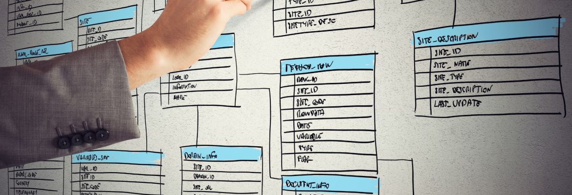 Hand with a marker mapping database fields to each other on a white back lit screen